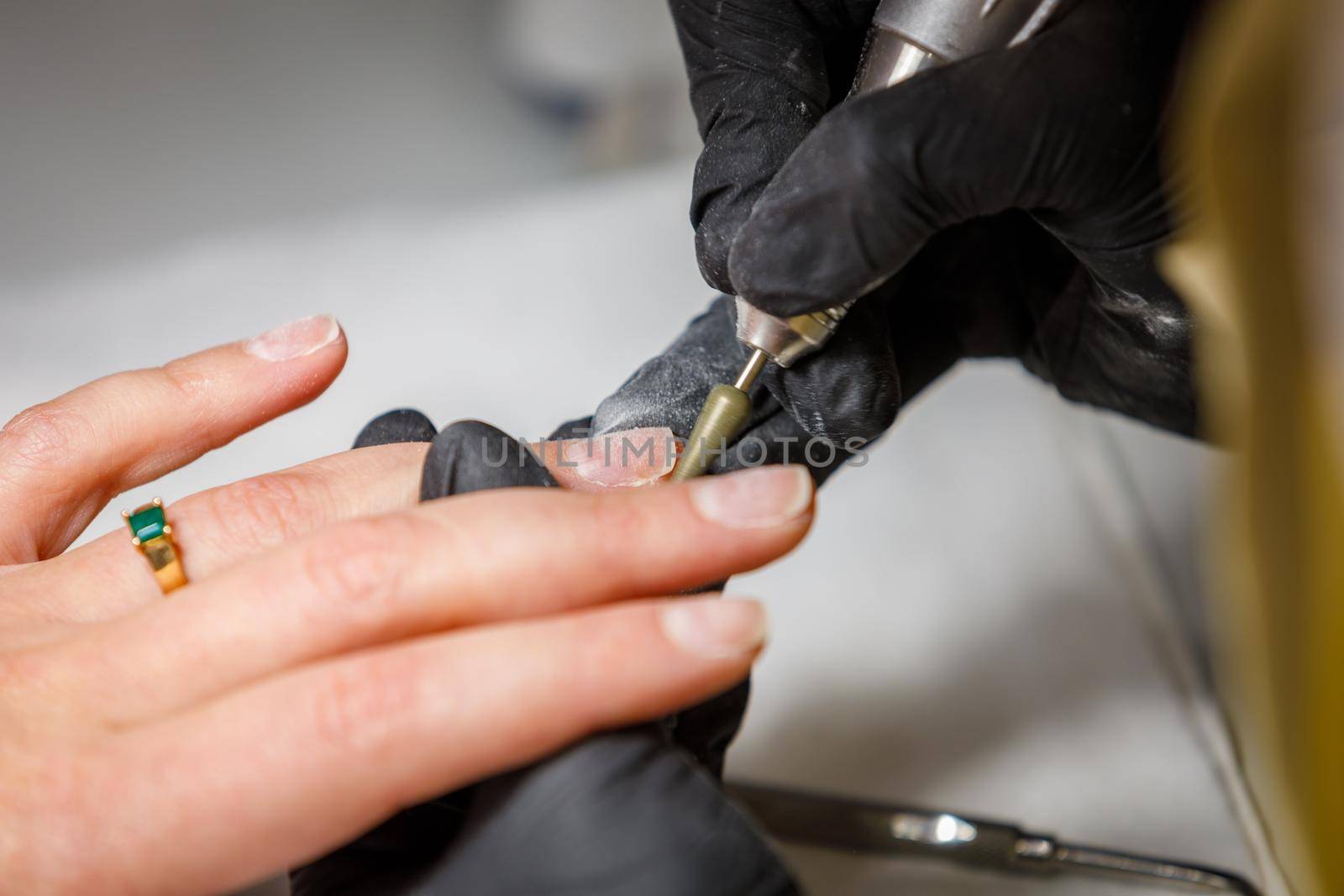 In the beauty studio, the master does hardware manicure. Removing gel polish with a cutter. Removes cuticles on the fingers.