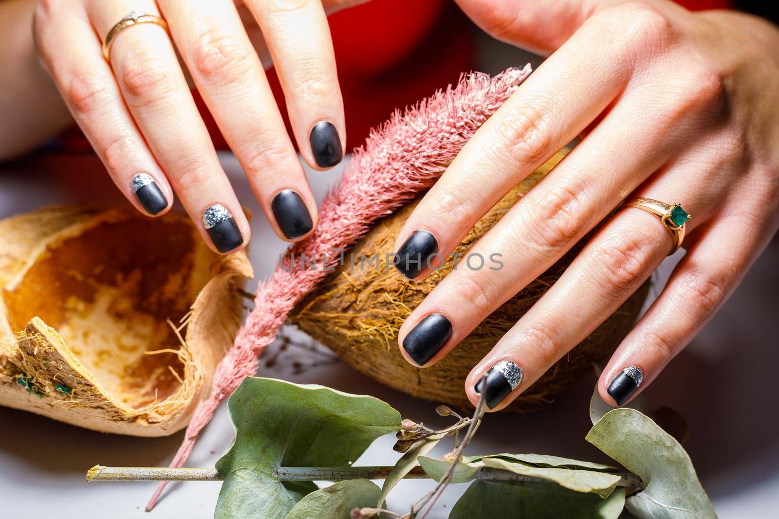 In a beauty salon, the master does a manicure, applies a pattern to the nail with a brush, black varnish with a golden pattern.
