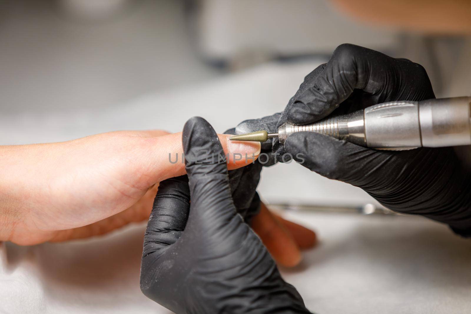 In the beauty studio, the master does hardware manicure. Removing gel polish with a cutter. Removes cuticles on the fingers.