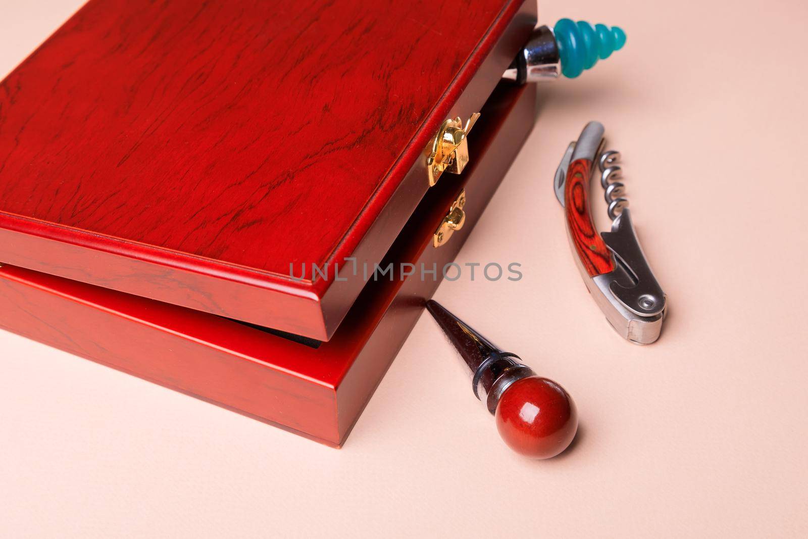 Gift set of corkscrew and removable lids. Wine corks and bottle openers in a wooden box on a pink background.