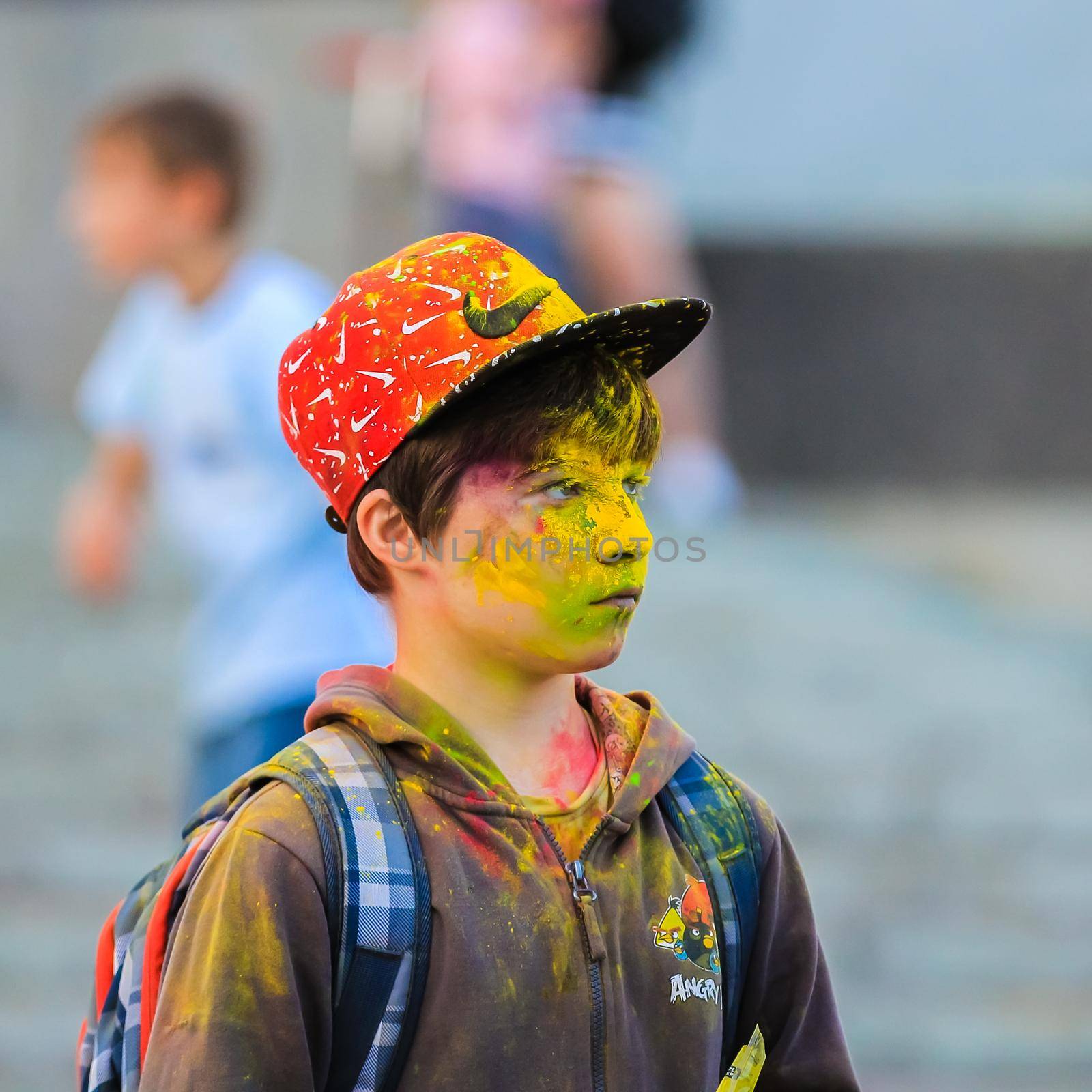 Russia, Moscow - June 25, 2017. Portrait of a young man with bright colors on his face. Laughs with happiness. Holi is a traditional holiday in India
