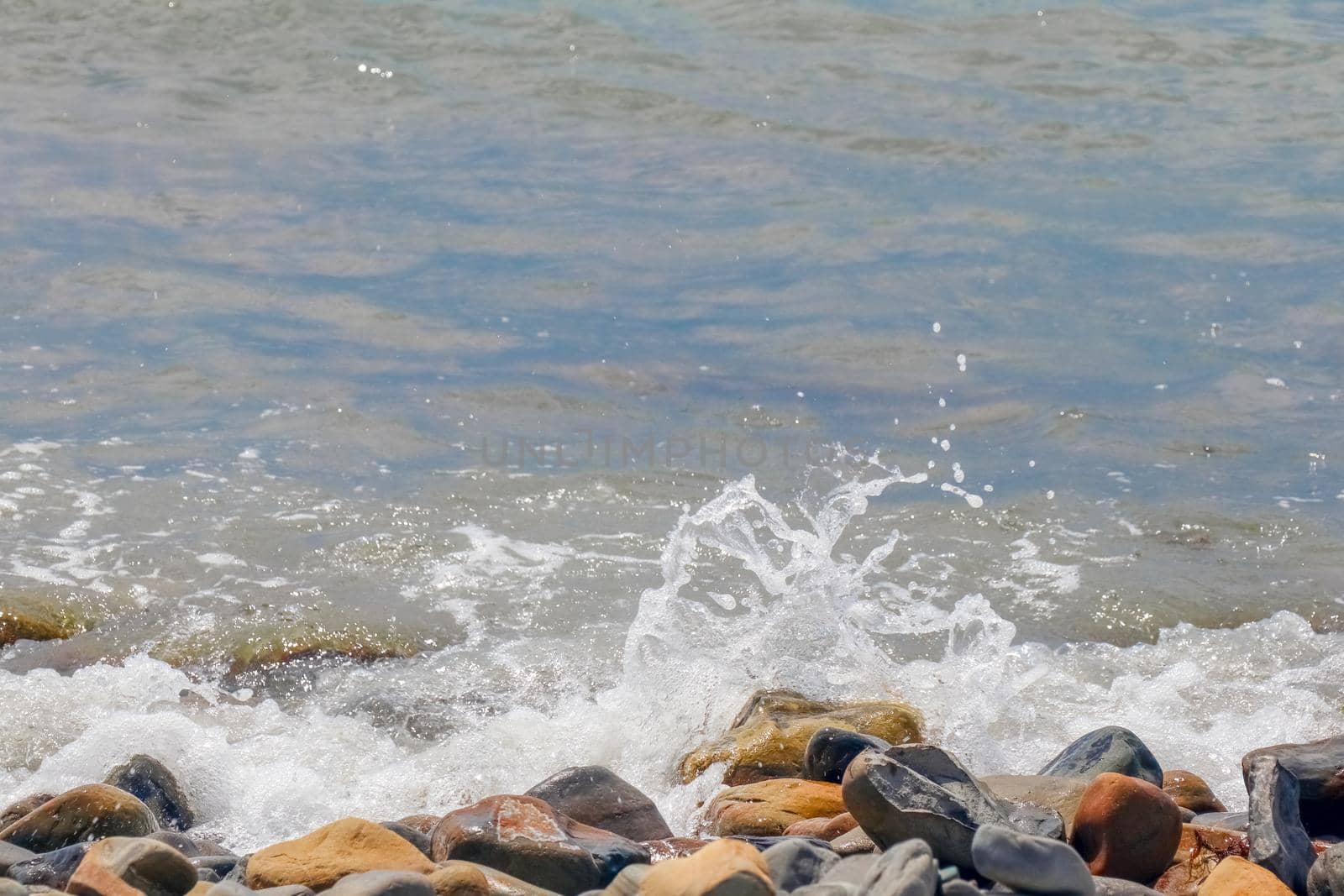 pebbles and stones on the beach. waves and splashes on the shore by roman112007