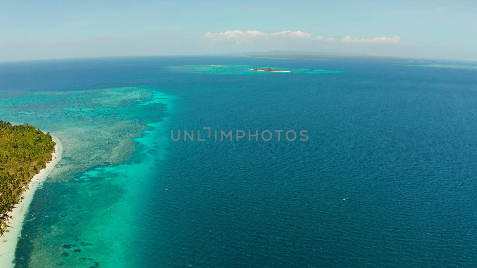 Aerial view of sandy beach on a tropical island with palm trees by coral reef atoll. Patongong Island with sandy beach. Summer and travel vacation concept.