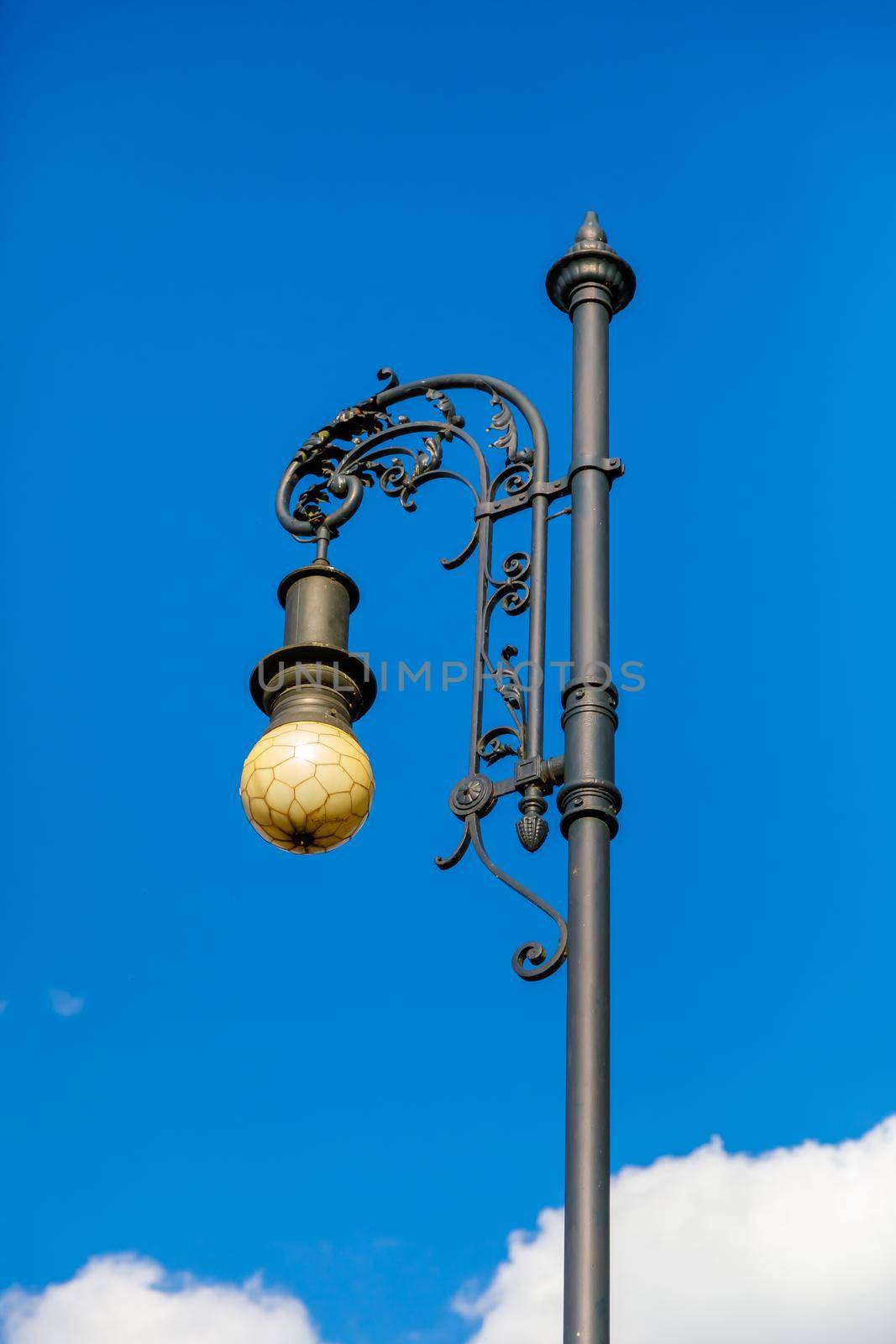 Luxurious antique street lamp made of black metal. Refined style, forging.