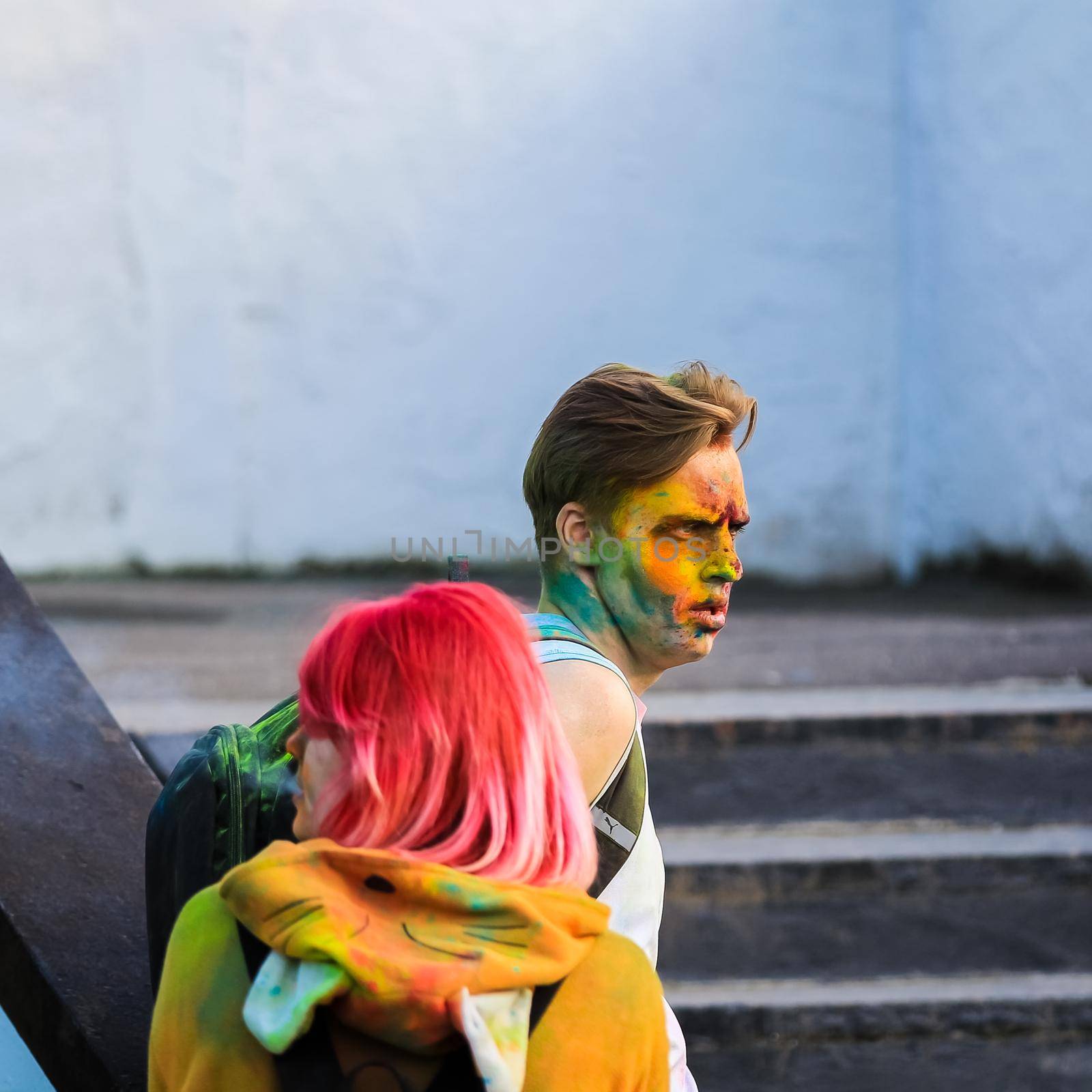 Russia, Moscow - June 25, 2017. Portrait of a young man with bright colors on his face. Laughs with happiness. Holi is a traditional holiday in India