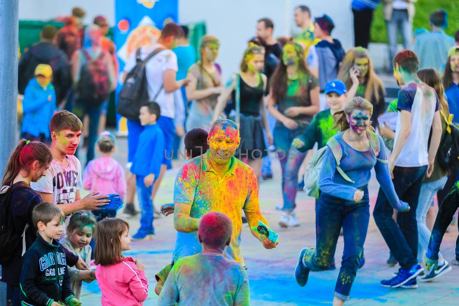 Russia, Moscow - June 25, 2017. Cheerful, young people throw themselves bright colors. Happy faces of adults and children are stained with paint. Holi is a traditional holiday in India