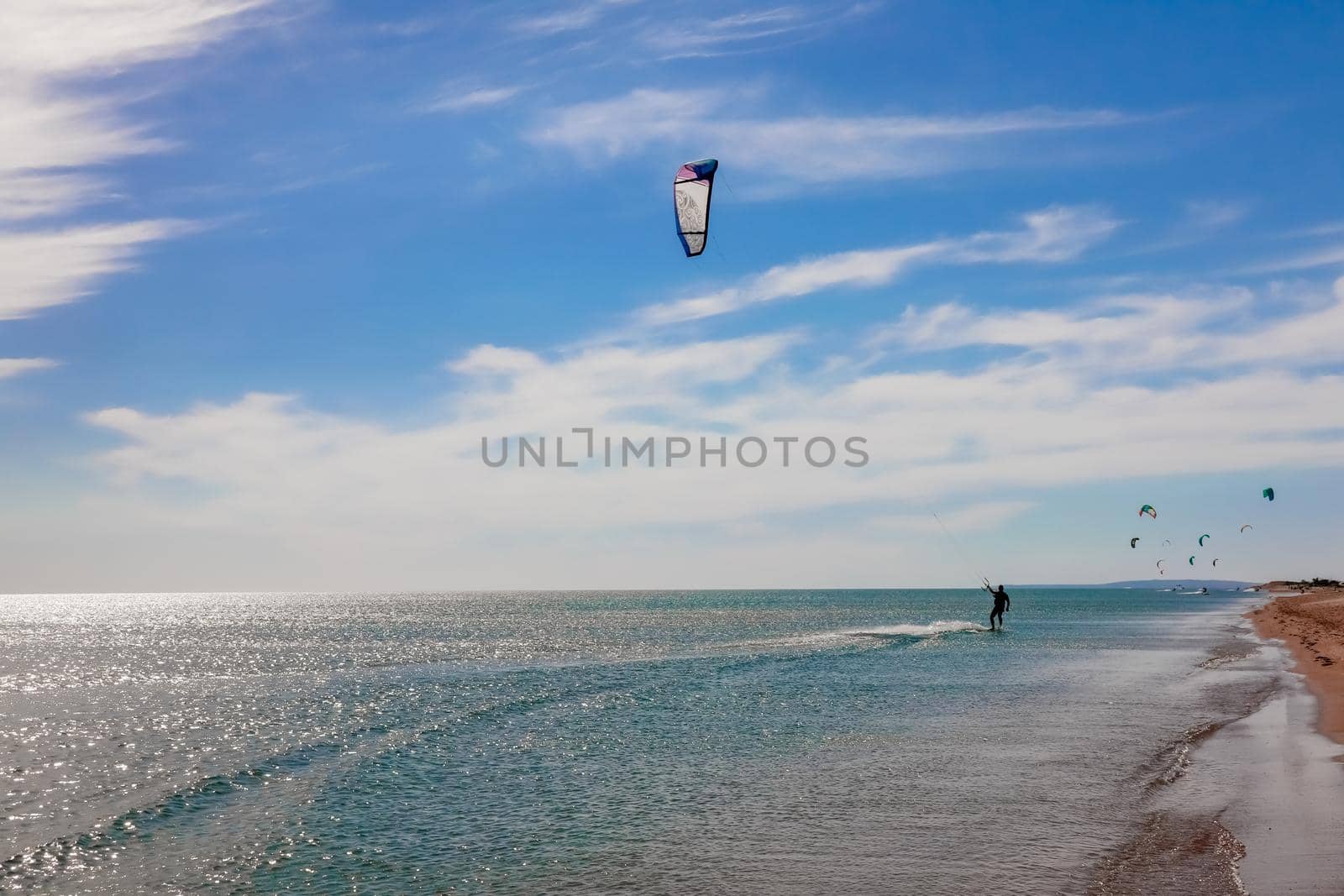 a kitesurfer surfing on the smooth azure water. recreational sport. A Man Rides A Kiteboarding In The Sea Water. extreme sport. High quality photo