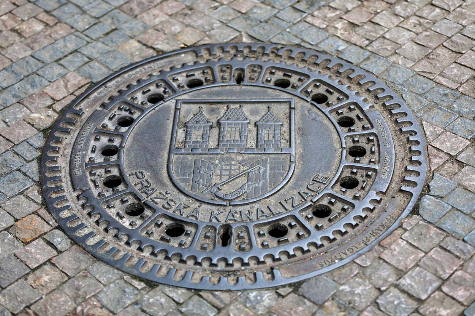 Prague, Czech Republic - April 13, 2018: Prazska Kanalizace manhole cover with the coat of arms of Prague and the tower of the bridge