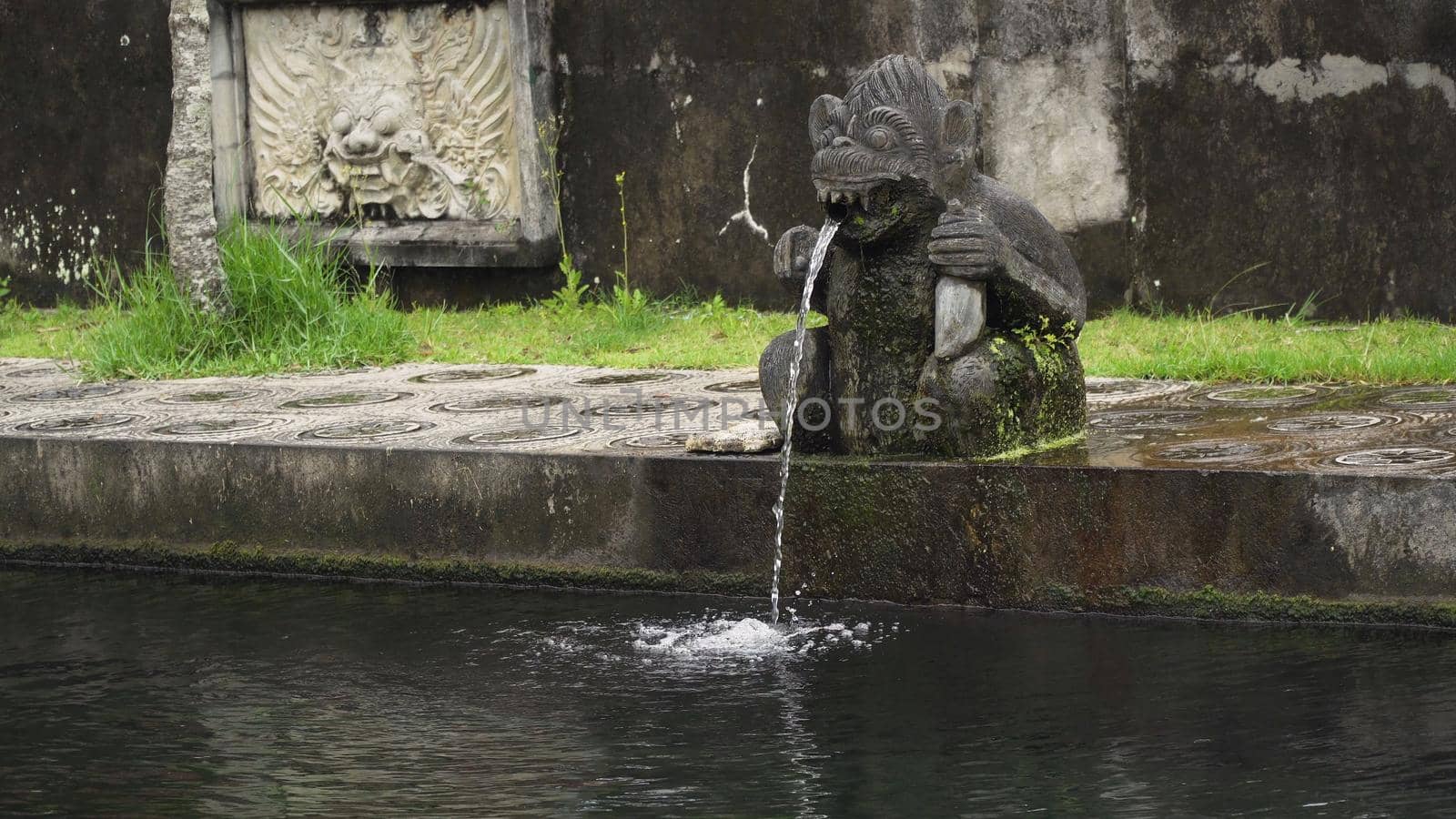 Hindu Balinese Water Palace Tirta Gangga with statues of the gods, fountains in the form of a wild boar on Bali island, Indonesia. Tirta Gangga the former royal water palace is a maze of pools and fountains surrounded by a lush garden and stone carvings and statues.