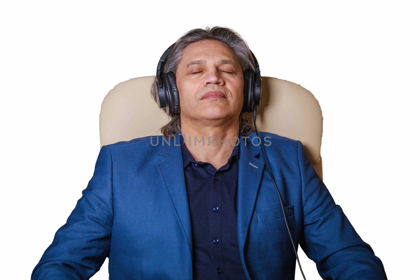 50-year-old man listens to music on headphones at home, sitting in a chair. Relaxing delight.