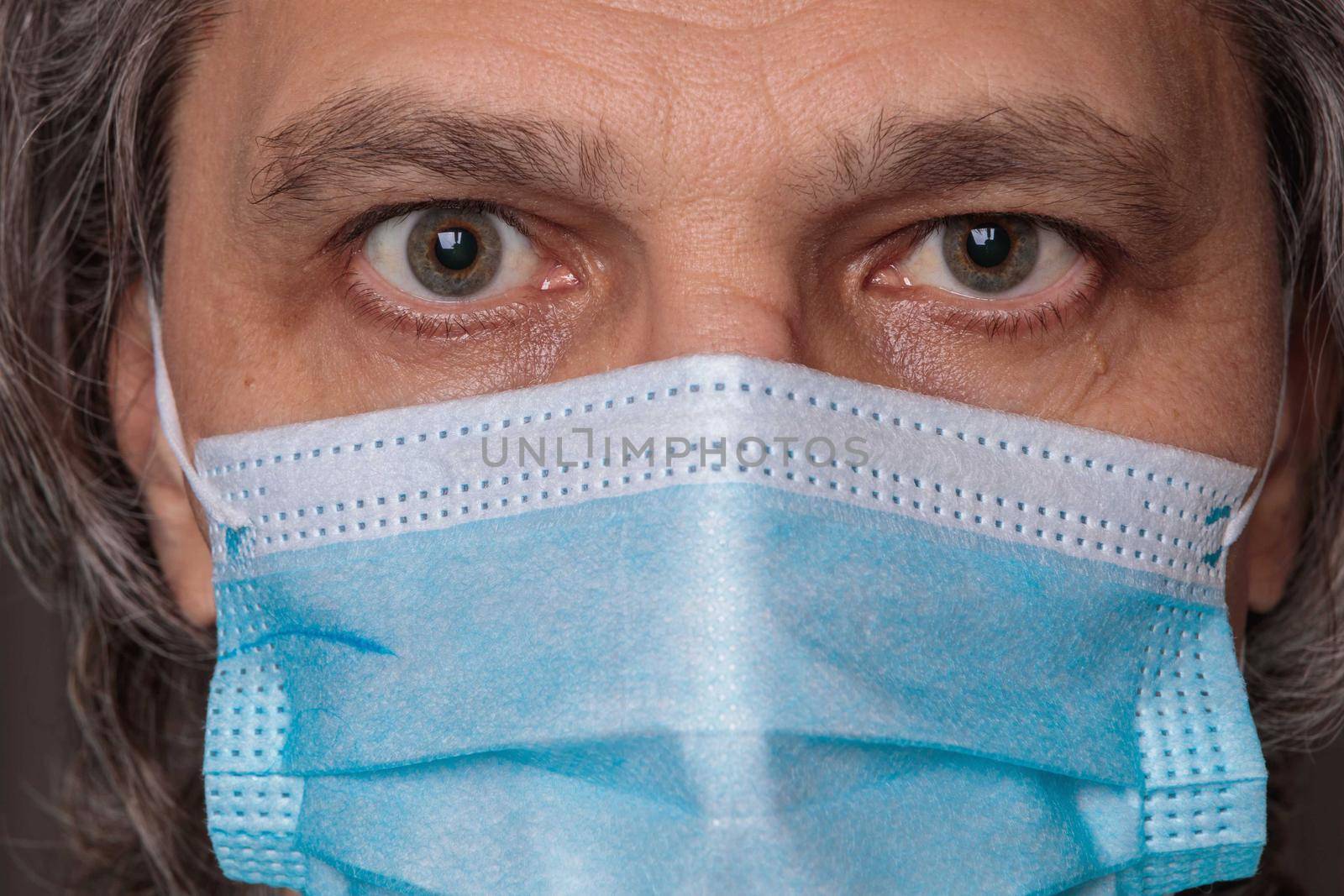 Adult man in a medical mask. Close-up eyes. Syringe in hand. Health safety concept