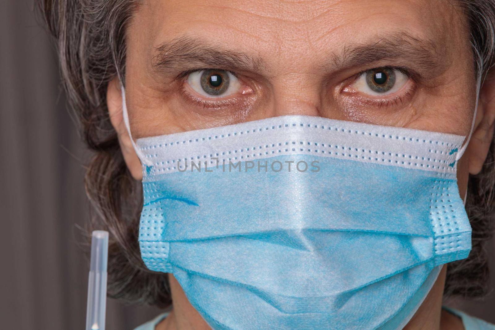 Adult man in a medical mask. Close-up eyes. Syringe in hand. Health safety concept