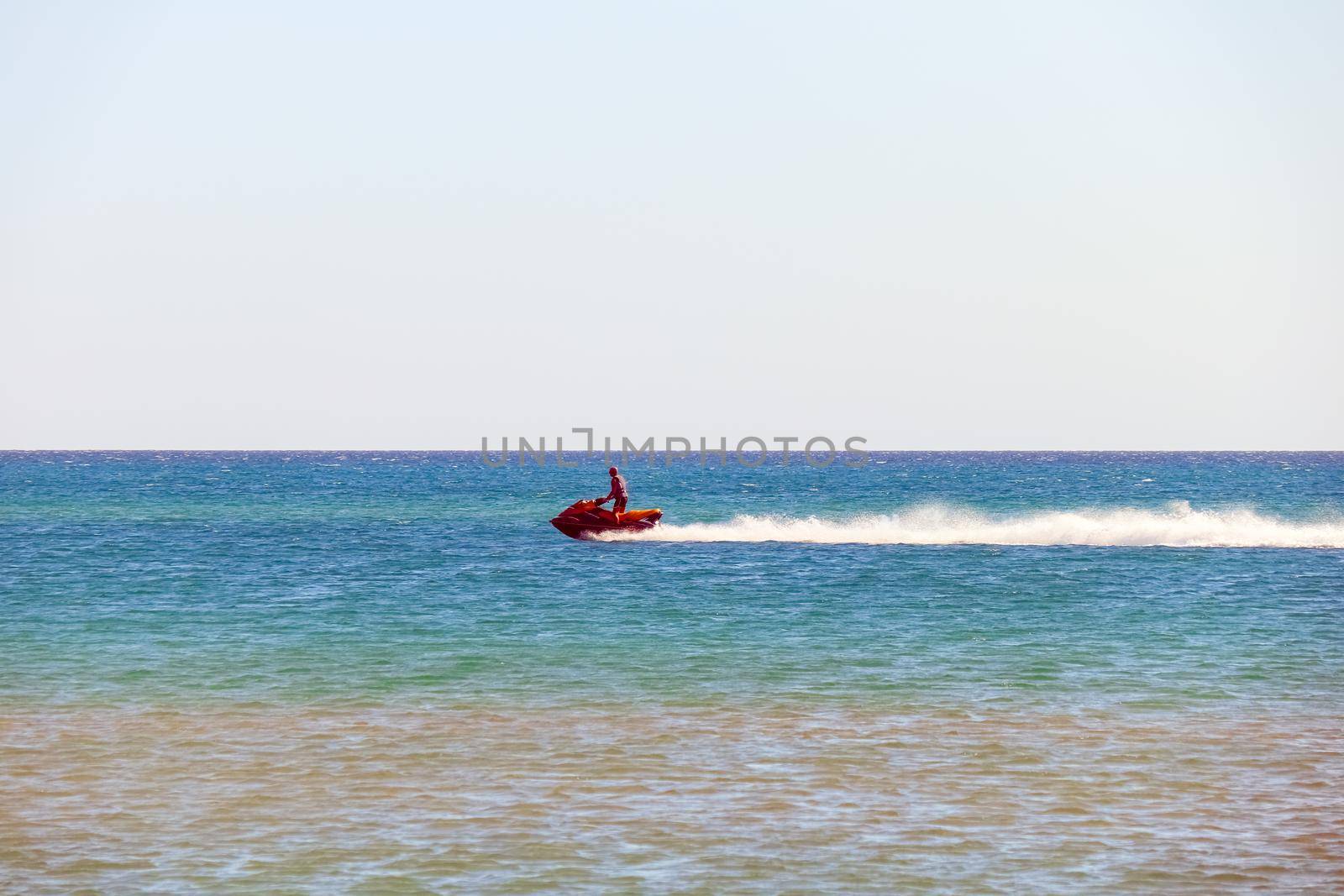 a man rides a jet ski in the open sea by roman112007