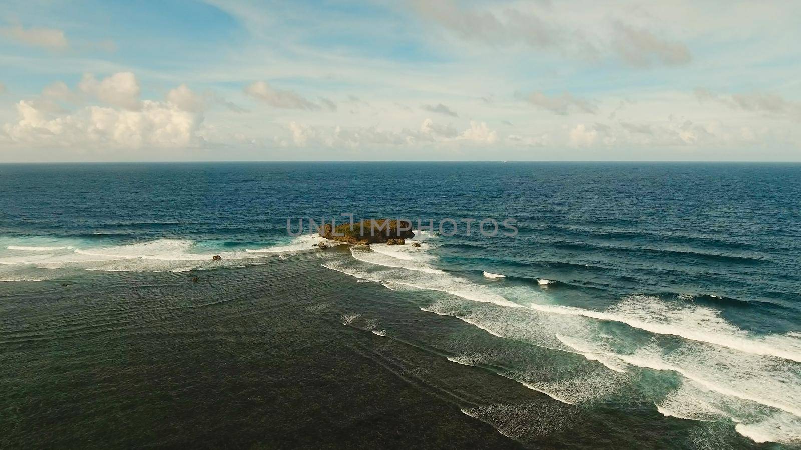 Large rock in the blue sea on a sunny day. Aerial view Rocky cliff in the ocean in the Siargao Island. Seascape: Ocean, sky, sea . Philippines.