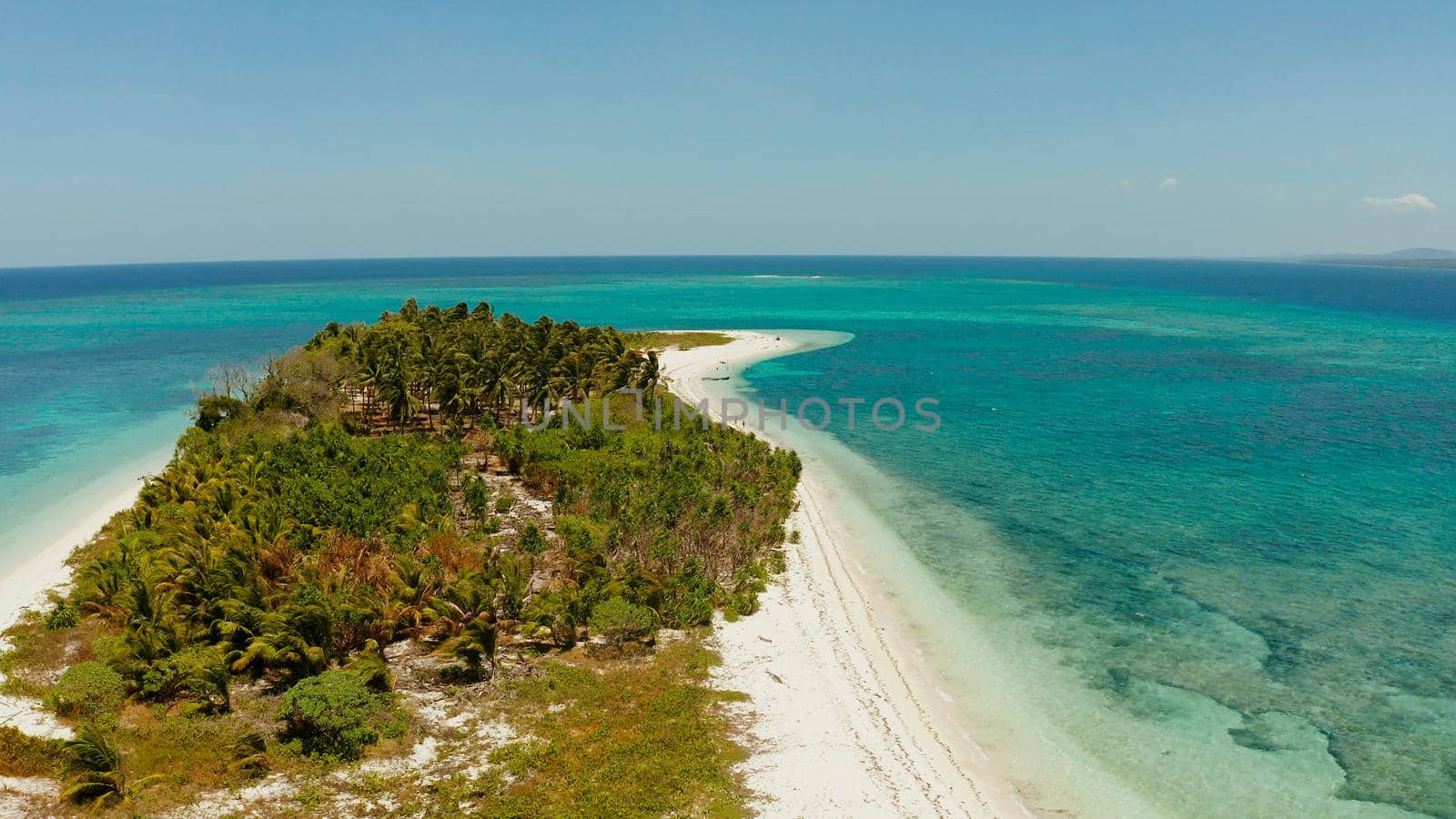 Tropical island on an atoll with beautiful sandy beach by coral reef from above. Canimeran Island and coral reef. Summer and travel vacation concept.