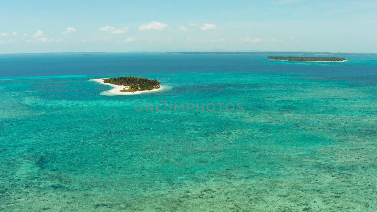 Small tropical island in the blue sea with a coral reef and the beach, top view. Summer and travel vacation concept. Canimeran Island, Balabac, Palawan, Philippines.