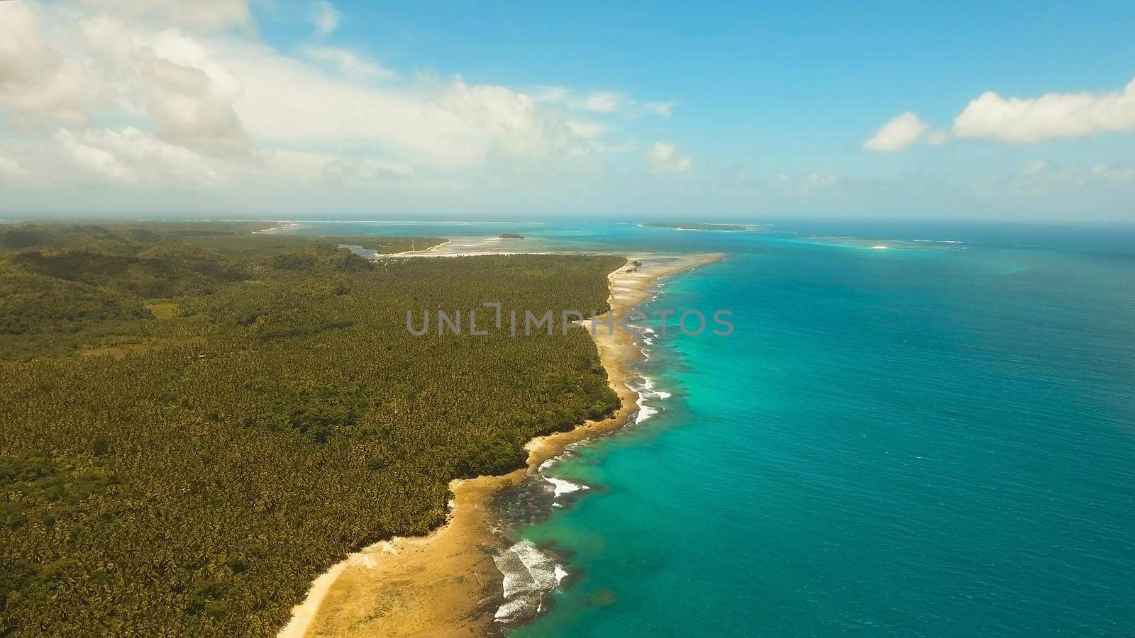 Aerial view of tropical beach on the island Siargao, Philippines. Beautiful tropical island with sand beach, palm trees. Tropical landscape: beach with palm trees. Seascape: Ocean, sky, sea . Philippines.