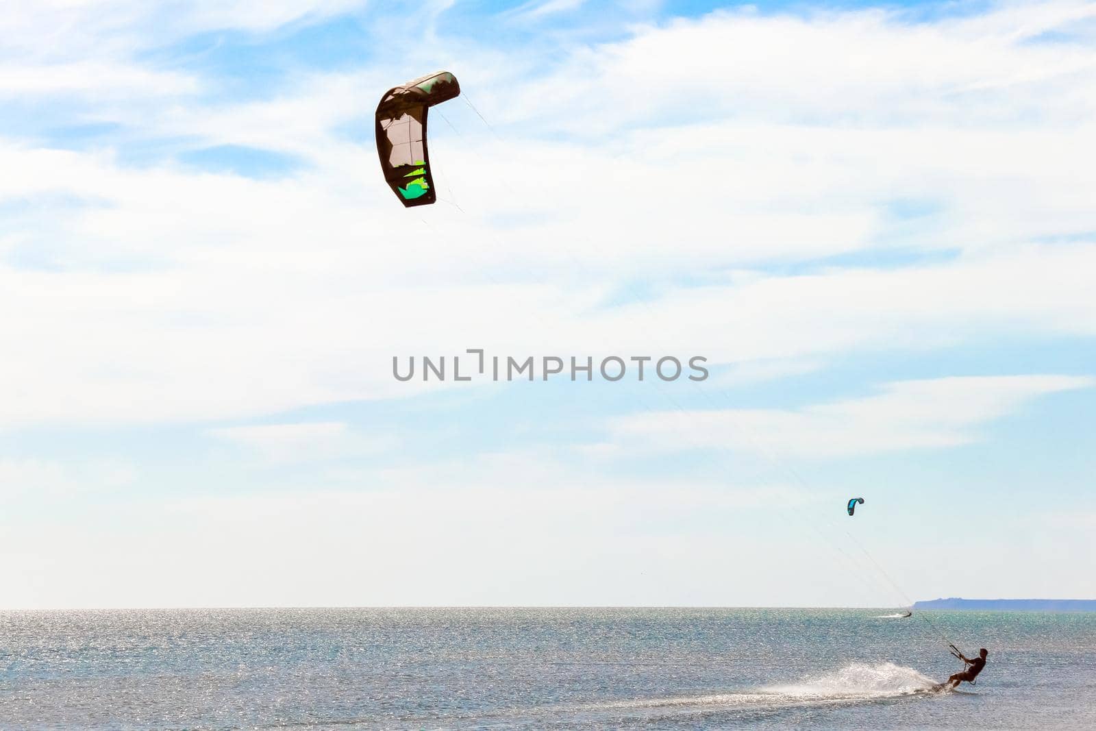 a kitesurfer surfing on the smooth azure water. recreational sport. A Man Rides A Kiteboarding In The Sea Water. extreme sport. High quality photo