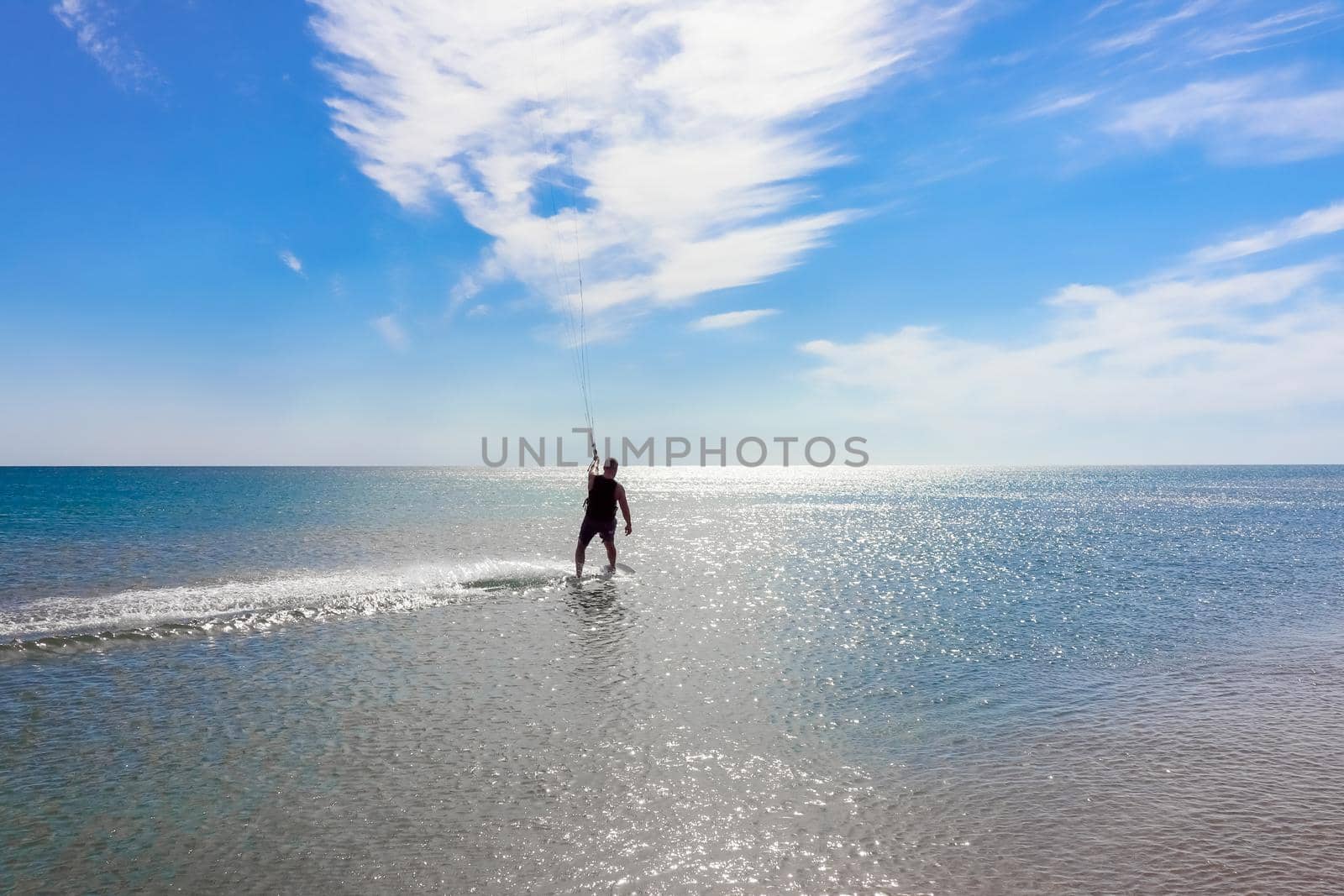 a kitesurfer surfing on the smooth azure water. recreational sport. A Man Rides A Kiteboarding In The Sea Water. extreme sport. Jump by roman112007