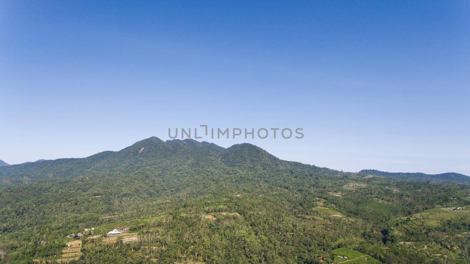 Aerial view of landscape, mountains covered with green forest, trees with sky and clouds, Bali,Indonesia. Slopes of the mountains are covered with forest in Asia. Travel concept.