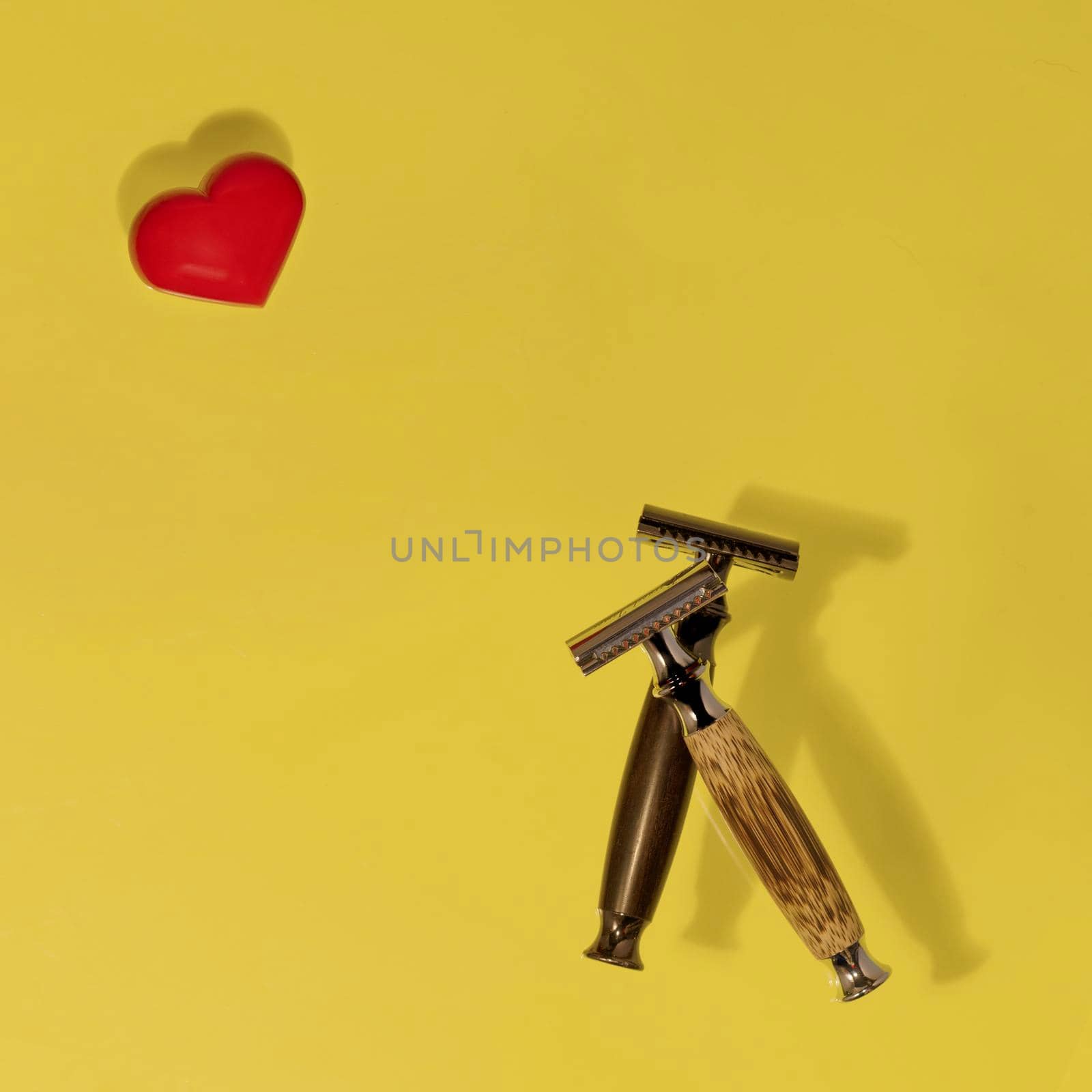 two razors and red heard on yellow background