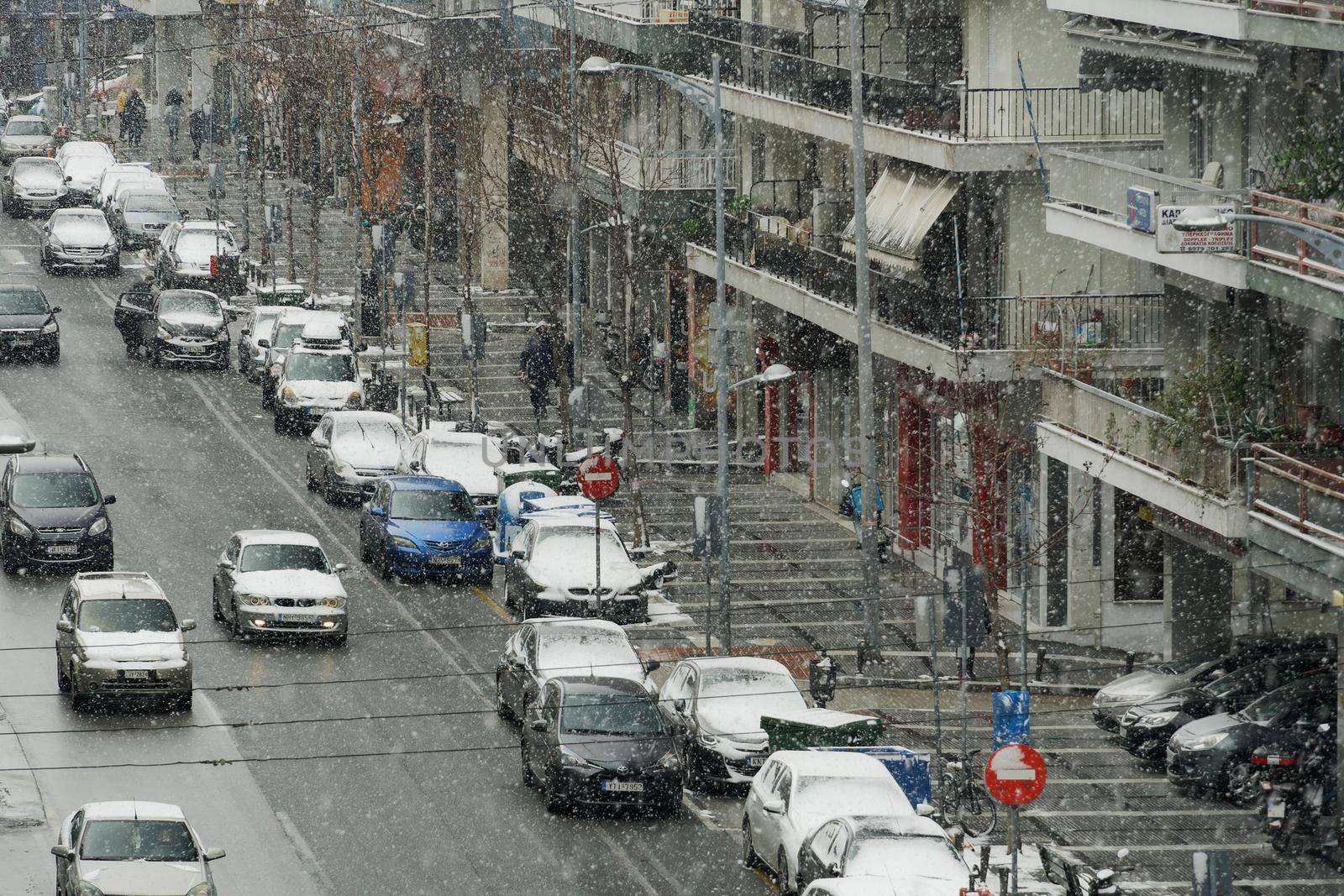 Snow falling at Vasilissis Olgas main street with some cars moving.