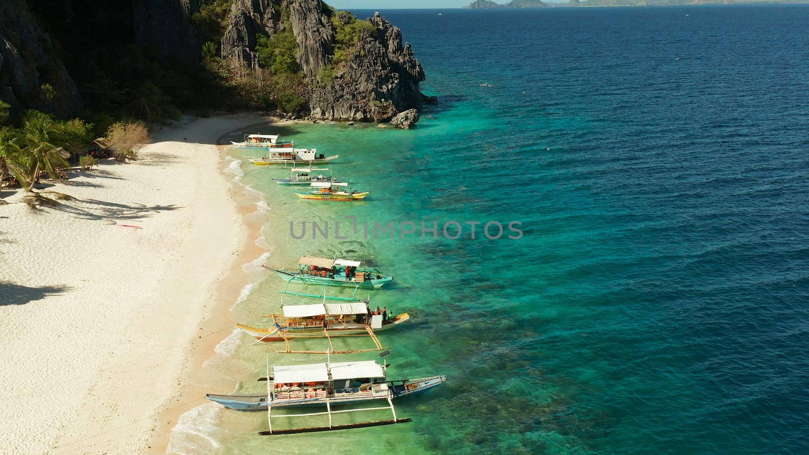 aerial view island with tropical sandy beach and palm trees. Malajon Island, Philippines, Palawan. tourist boats on coast tropical island. Summer and travel vacation concept. beach and blue clear sea water