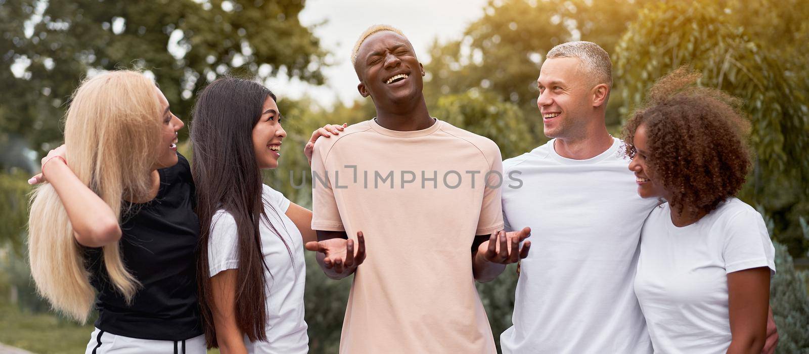 Multi-ethnic group teenage friends. African-american asian caucasian student spending time together Multiracial friendship Happy smiling People dressed black white sportswear meeting outdoor