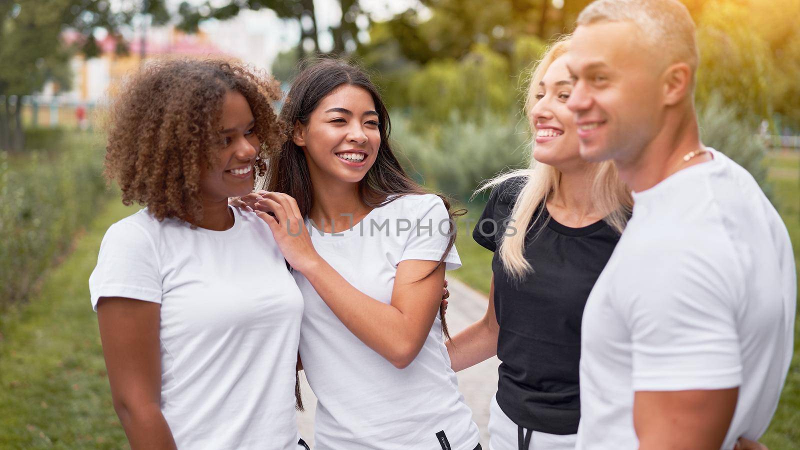 Multi-ethnic group teenage friends. African-american asian caucasian student spending time together Multiracial friendship Happy smiling People dressed black white sportswear meeting outdoor