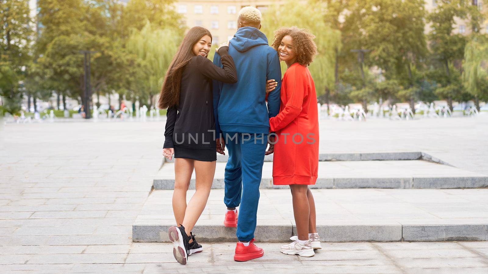 Multi ethnic friends outdoor. Two woman in love with one guy Diverse group people Afro american asian spending time together Multiracial male female student walking park outdoors