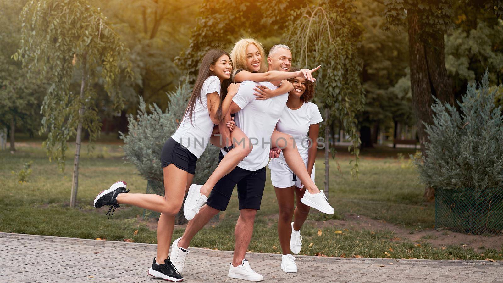 Multi-ethnic group teenage friends. African-american asian caucasian student spending time together piggy back rides having fun Multiracial friendship Happy smiling People dressed sportswear