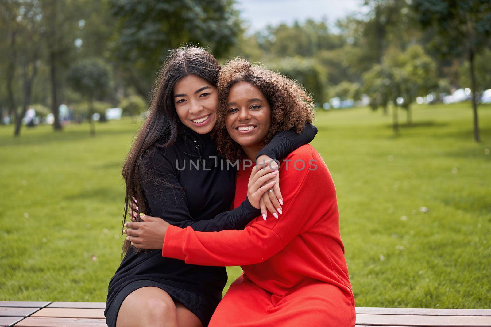 Diversity and feminity concept. Happy smiling Confident young mixed race women sitting bench park outdoor Asian and african american female resting on nature summer day