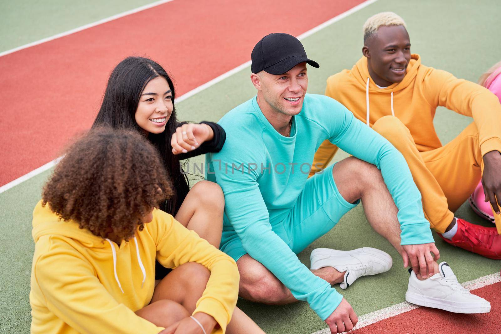 Multi-ethnic group teenage friends. African-american asian caucasian student spending time together Multiracial friendship Happy smiling People dressed colorful sportswear meeting outdoor sportground