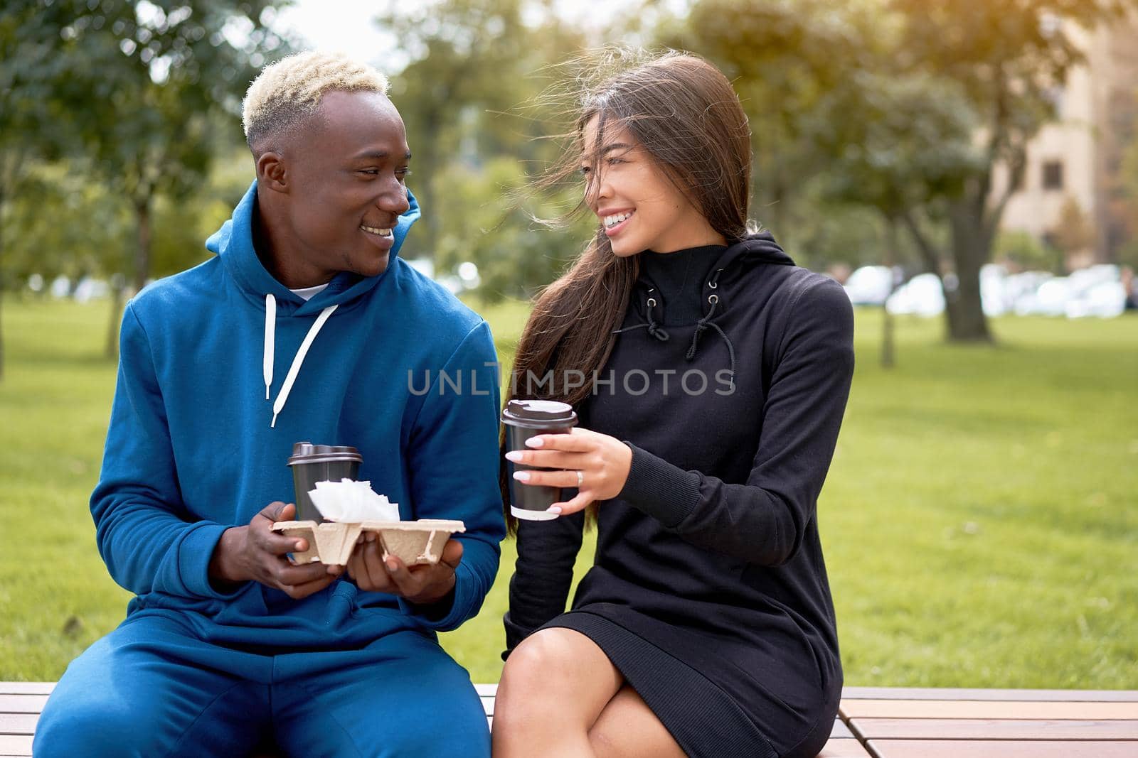 African american man proposes coffee asian woman Multiethnic friendship. Interracial relationship Young adult international couple drink hot beverage spending time together outdoor bench park Summer