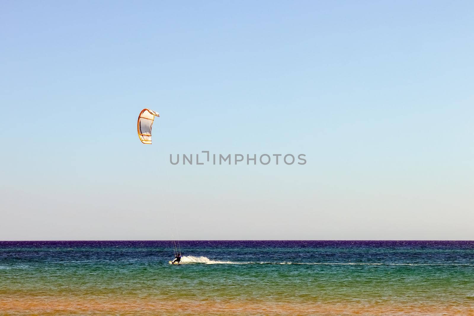 a kitesurfer surfing on the smooth azure water. recreational sport. A Man Rides A Kiteboarding In The Sea Water. extreme sport. High quality photo