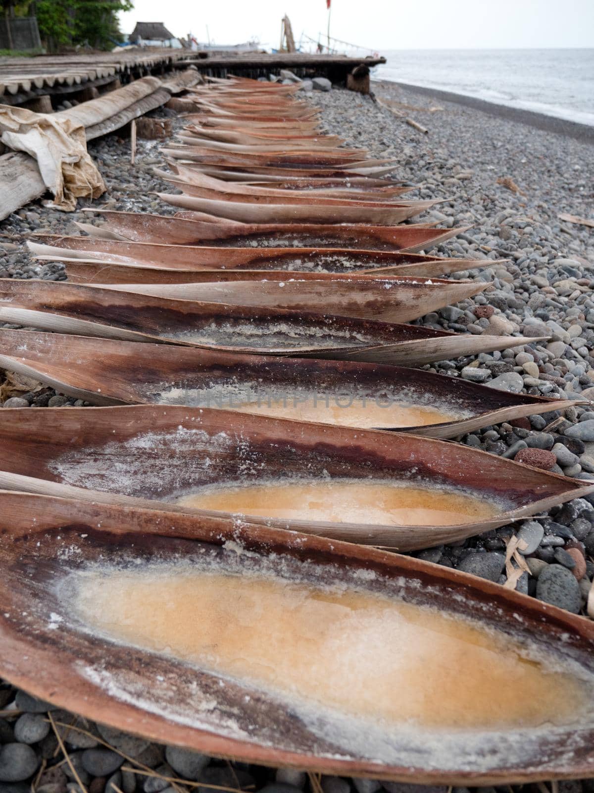 Production of sea salt in the Bali,Indonesia. Salt crystallizes out of the ground in salt farm, filled with natural salt from the sea.