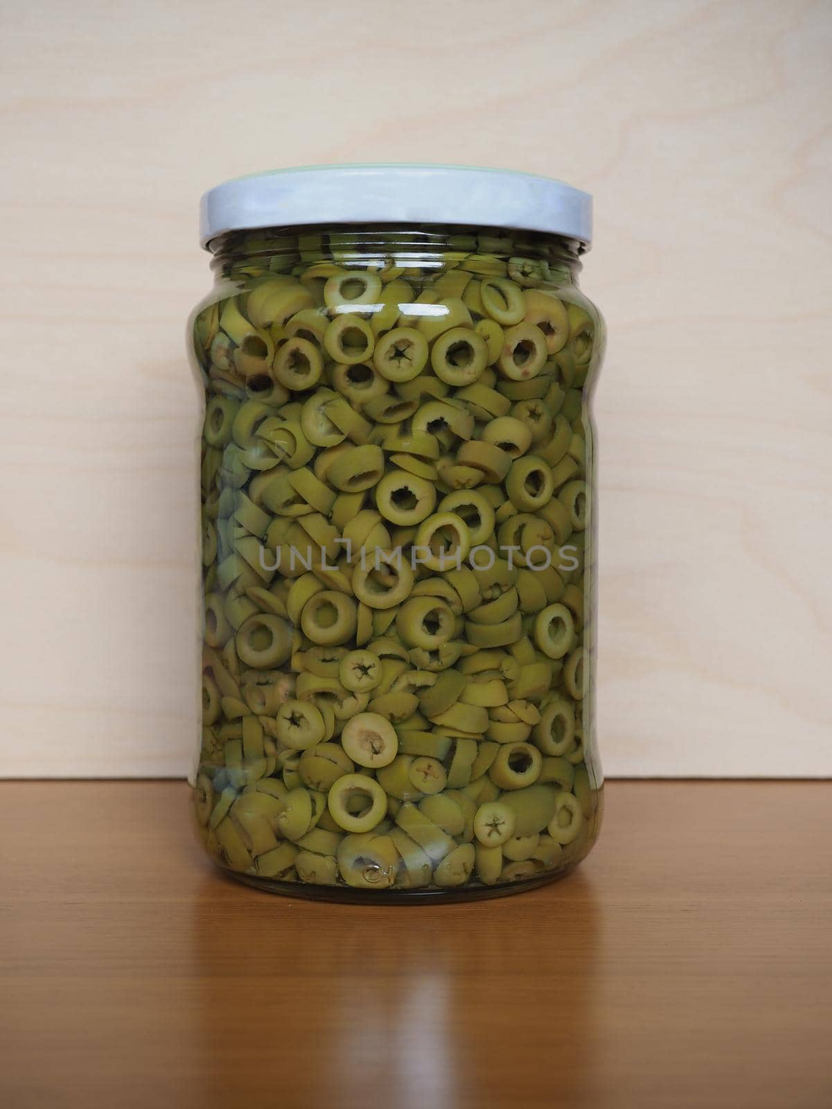 sliced green olives in brine in a glass jar