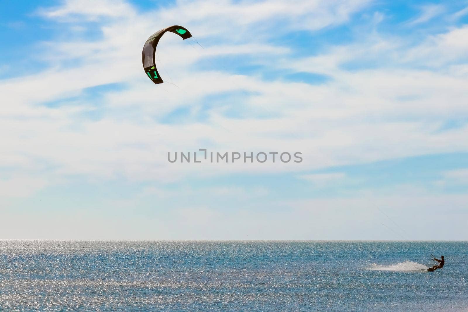 a kitesurfer surfing on the smooth azure water. recreational sport. A Man Rides A Kiteboarding In The Sea Water. extreme sport. High quality photo