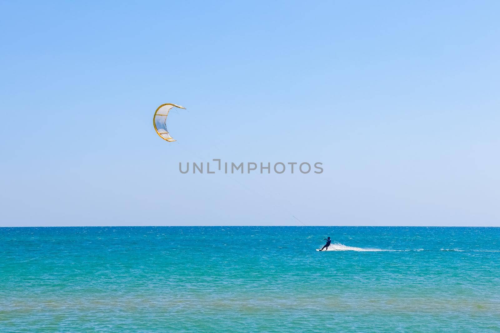 a kitesurfer surfing on the smooth azure water. recreational sport. A Man Rides A Kiteboarding In The Sea Water. extreme sport. High quality photo