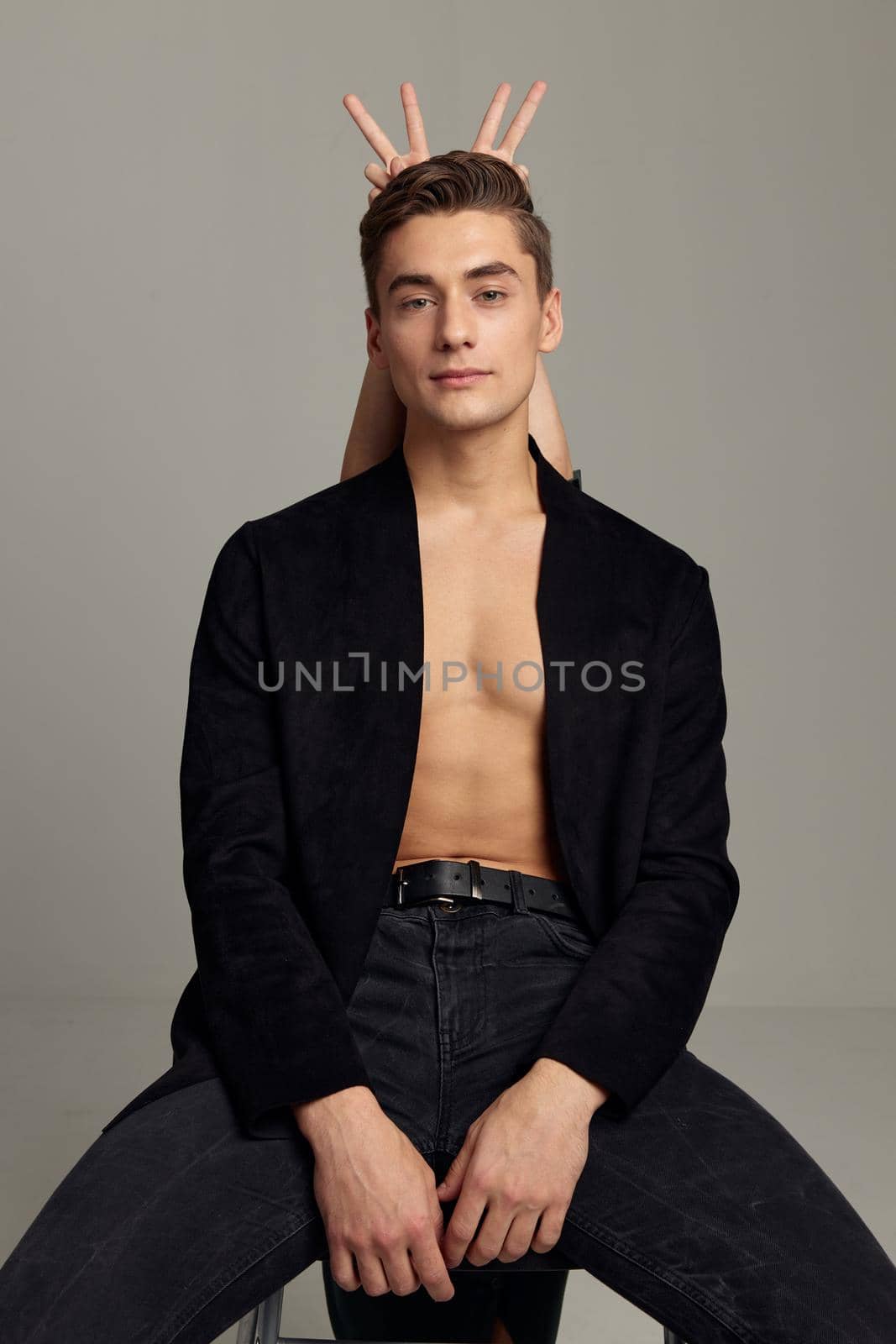 handsome man black shirt sitting on a chair fingers behind his head. High quality photo