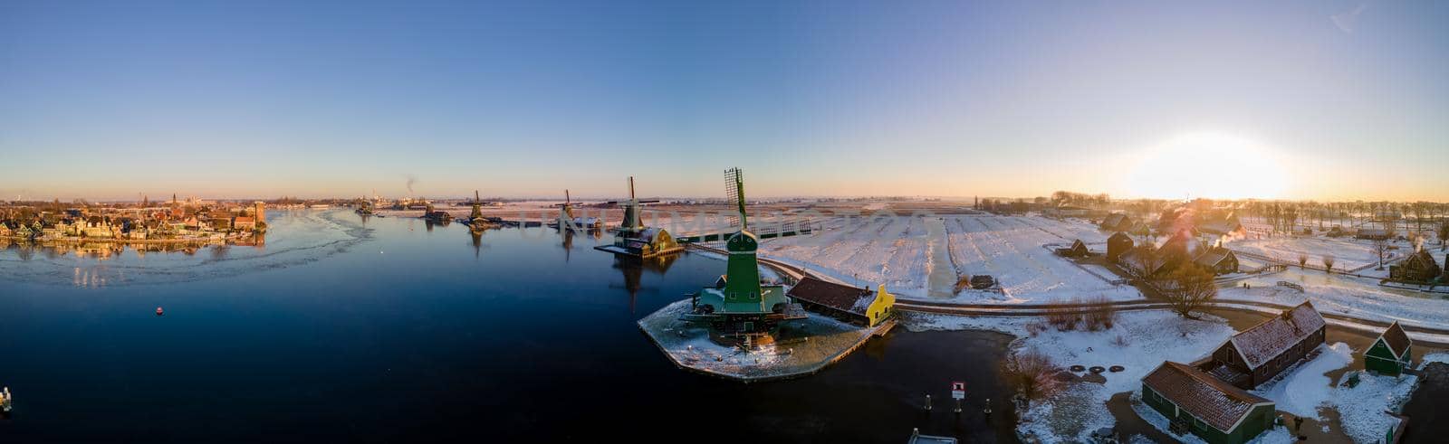 panoramic view over the Zaanse Schans windmill village snow covered during winter, Zaanse Schans wind mills historical wooden mills in the Netherlands by fokkebok