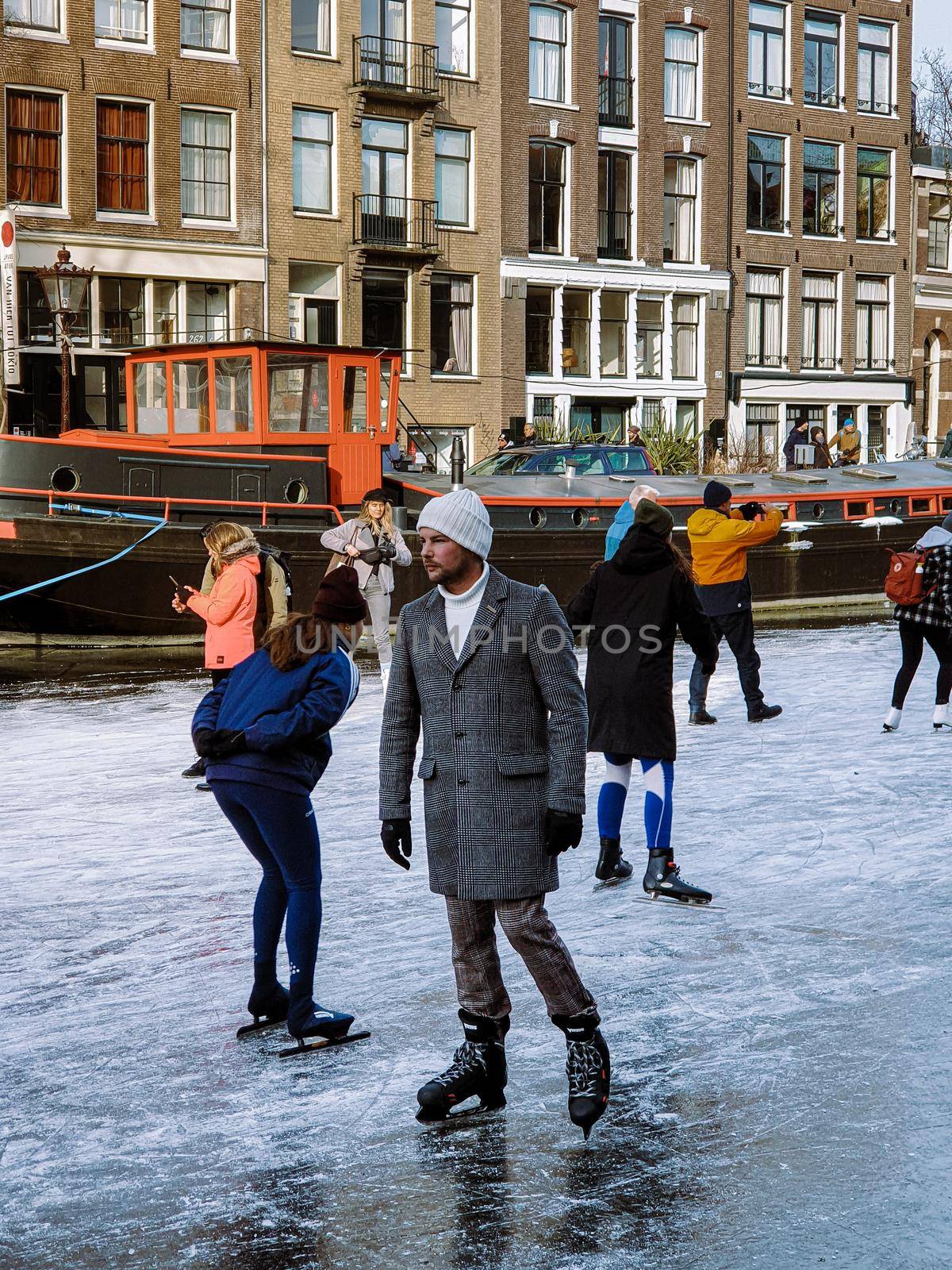 Amsterdam Netherlands, frozen canals and people ice skating in Amsterdam by fokkebok