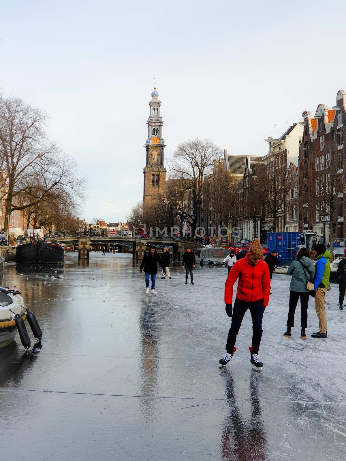 Amsterdam Netherlands, frozen canals and people ice skating in Amsterdam by fokkebok