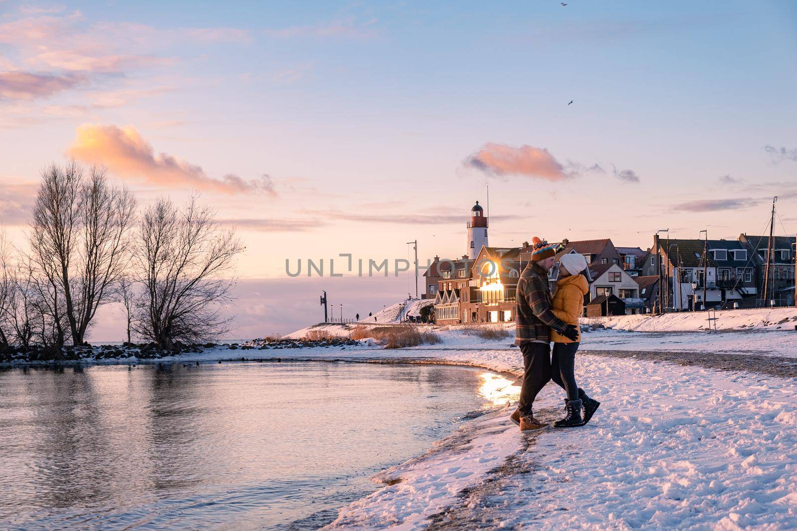 couple men and woman by the lighthouse of Urk Netherlands during winter in the snow. Winter weather in the Netherlands by Urk