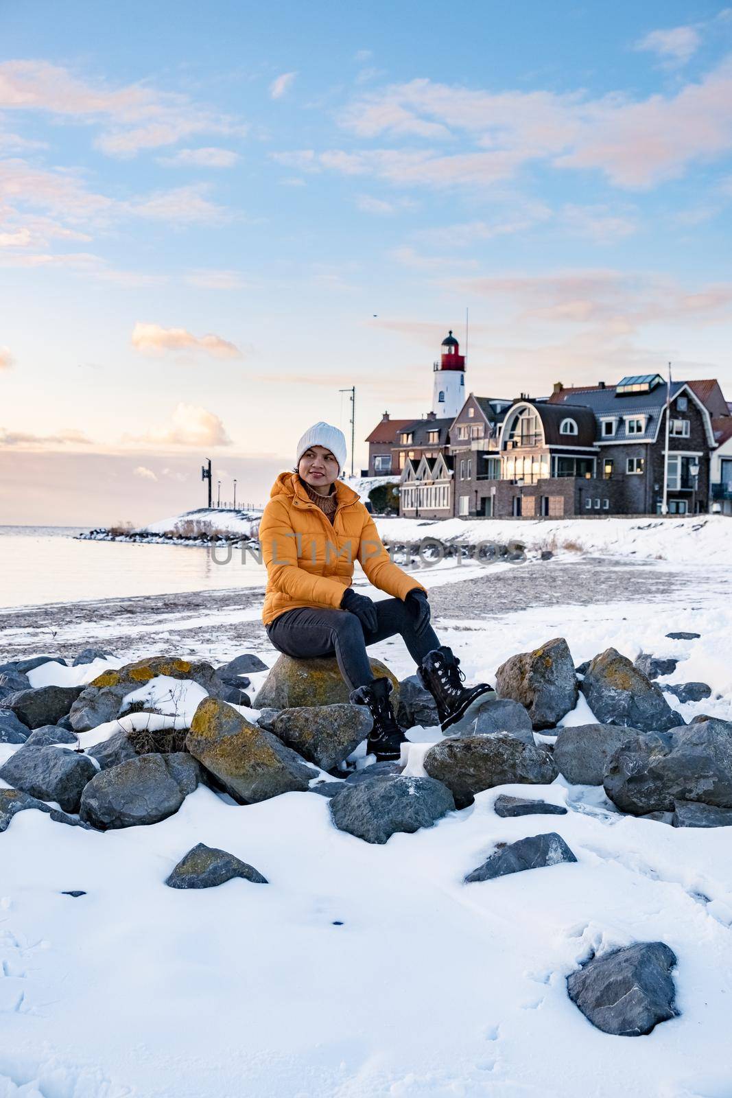 woman by the lighthouse of Urk Netherlands during winter in the snow. Winter weather in the Netherlands by Urk