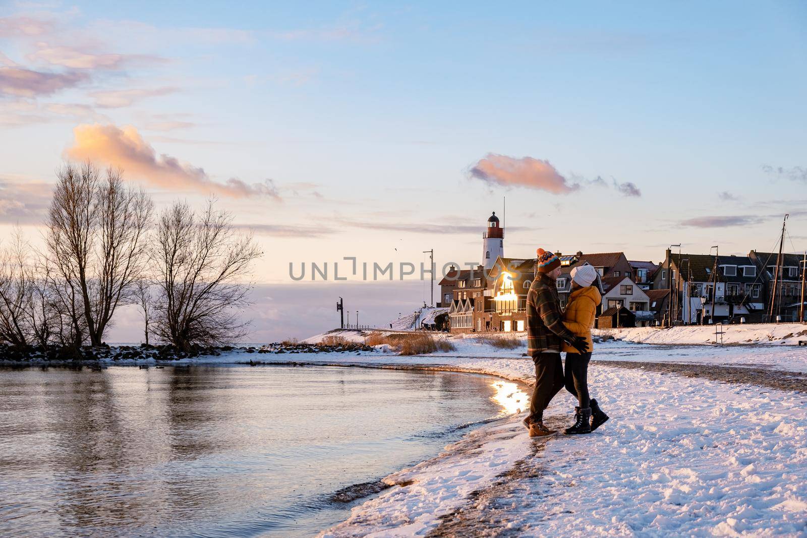 couple men and woman by the lighthouse of Urk Netherlands during winter in the snow. Winter weather in the Netherlands by Urk