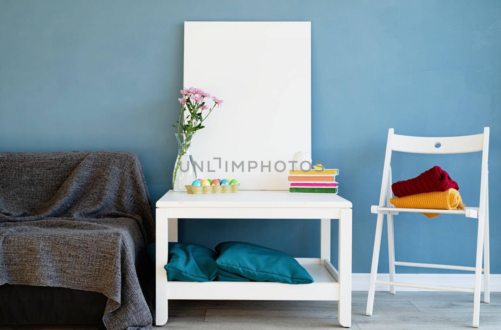 Mock up white poster frame on coffee table in blue room. White blank canvas in interior