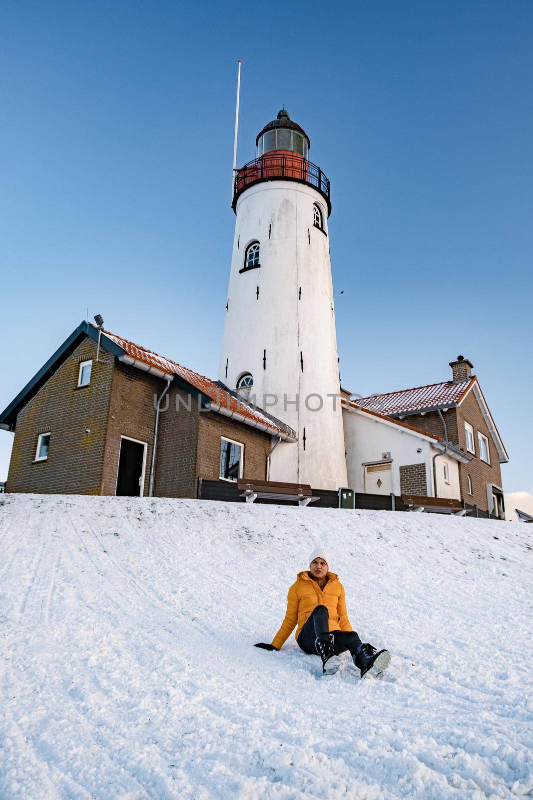 woman by the lighthouse of Urk Netherlands during winter in the snow by fokkebok