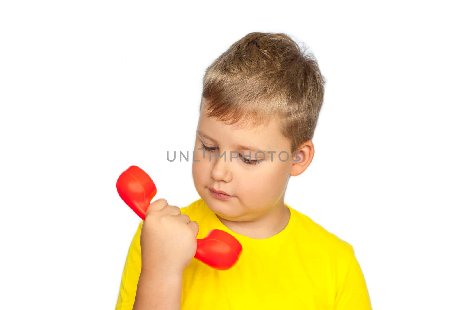 A boy in a yellow T-shirt on a white background with a red telephone receiver. The concept of a banner with information. Space for the text. Concepts