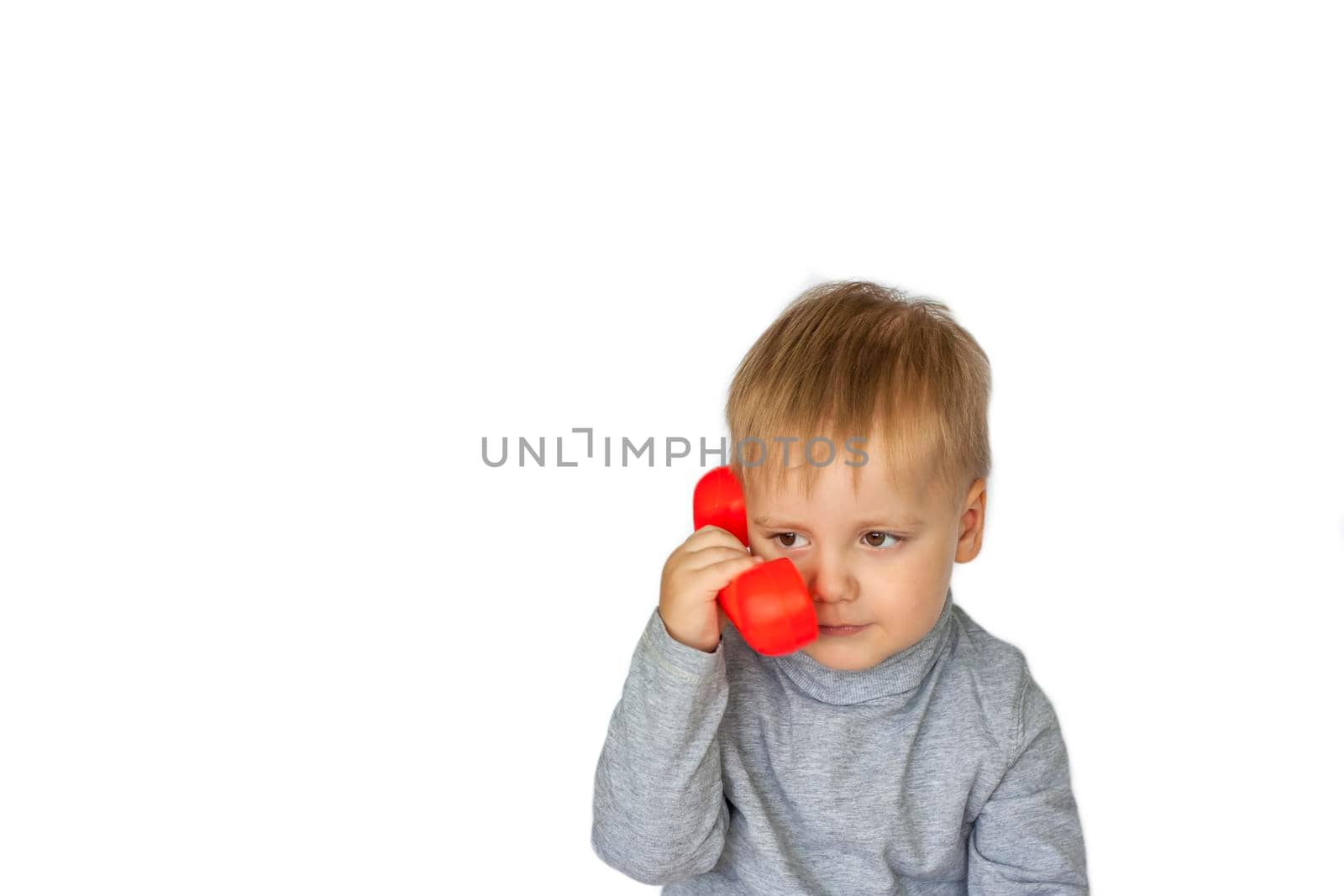 A boy in a gray sweatshirt on a white background with a red telephone receiver. Indicates to call here. The concept of a banner with information. Space for the text. Concepts